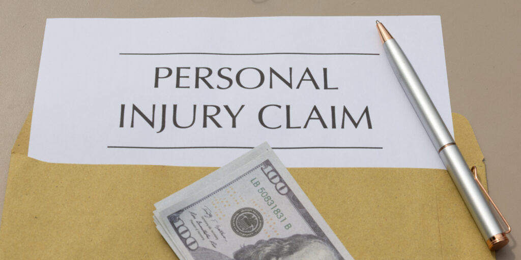 Personal injury claim document with a stack of hundred-dollar cash bills and a pen, illustrating how insurance companies calculate a personal injury settlement payout in Florida.